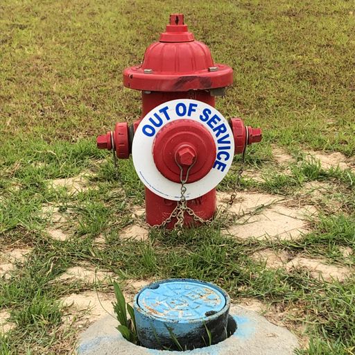 Red fire hydrant with out of service sign near water tap.