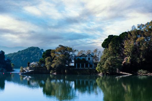 A scenic view of the calm river in the village in Spain under a cloudy sky