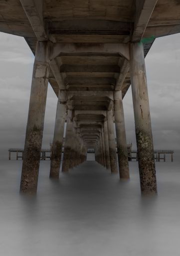 A low angle shot of a wooden pier at a beach on a foggy day