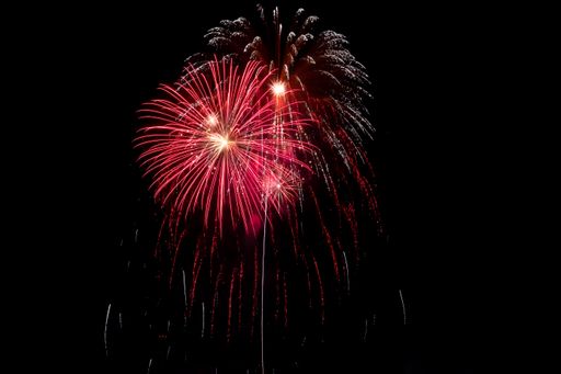 Bright fiery beams of light from exploding pyrotechnics against the black night sky. Fireworks, power and fun.