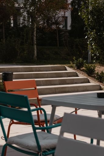 A vertical shot of a staircase in a park with chairs and tables of an outdoor cafe