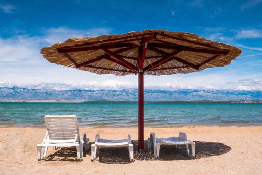 A view of the beautiful blue sky and straw beach umbrella.