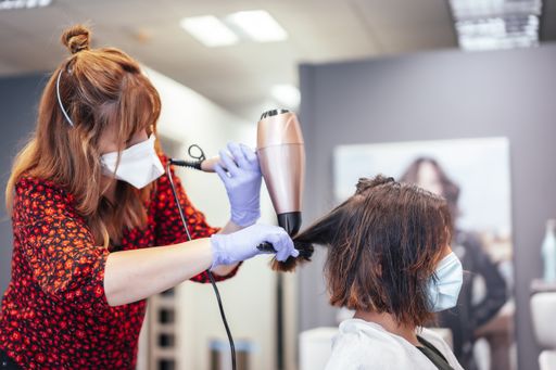 A selective focus shot of a Caucasian female getting hair dry in a beauty salon during pandemic