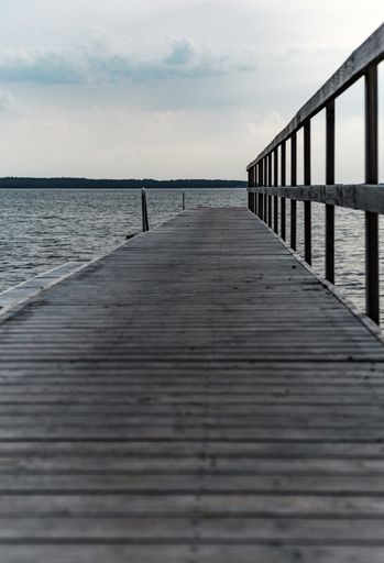 A vertical shot of a wooden pier at the cpast of the beautiful see under a cloudy sky