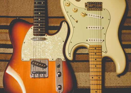 A closeup shot of two electric guitars put close to each other on a patterned background