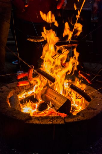 A closeup of a camp fire with flames and wood pieces at night