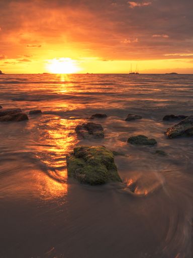 A vertical shot of the beautiful sunset during tide on the island of Ibiza.