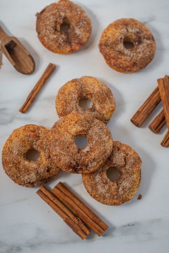A Top view of cinnamon donuts on a white background with cinnamon sticks