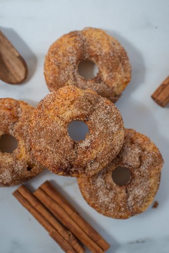A top view of cinnamon donuts on a white background with cinnamon sticks