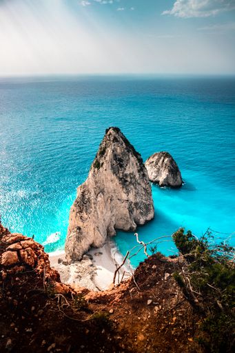 A vertical shot of Rocks in the sea, morning sun over the Mediterranean Sea. Cliff with sandy beach on Zakynthos