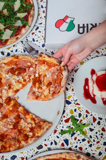 A vertical shot of a hand taking out a slice of pizza from a plate