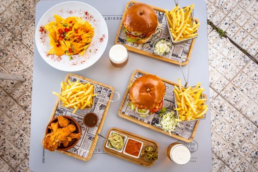 A closeup of a snack table with delicious burgers and french fries on a wooden board