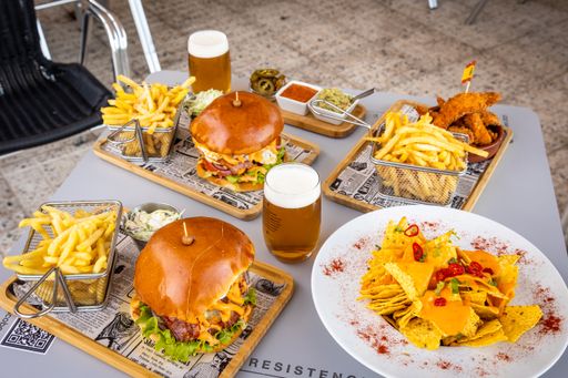 A closeup of a snack table with delicious burgers and french fries on a wooden board