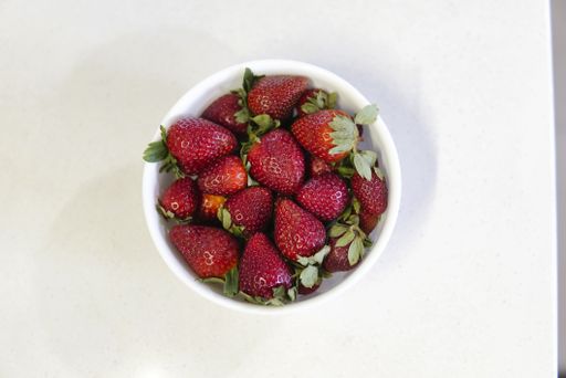 A high angle shot of fresh and delicious strawberries in a bowl isolated on a white background
