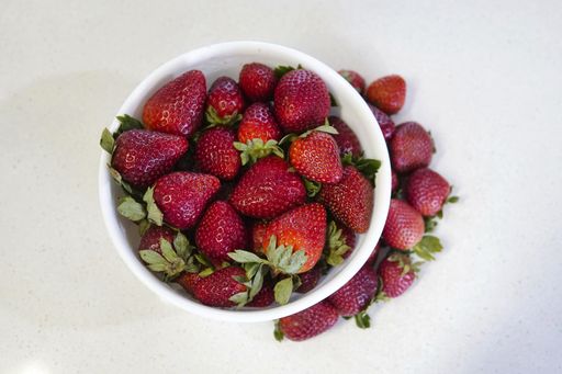 A high angle shot of fresh and delicious strawberries in a bowl isolated on a white background