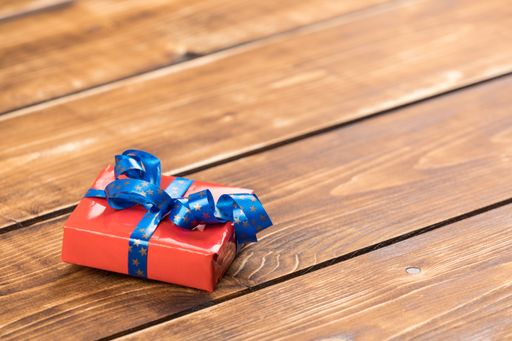 A closeup shot of a red present with a blue ribbon on the wooden background