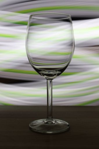 A vertical selective focus shot of an empty wine glass with blurry lights in the background