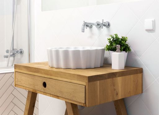 The neat and modern bathroom sink decorated with a vase captured in a white bathroom