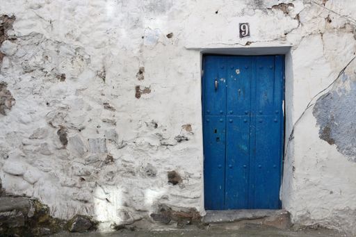 An old blue wooden door on a white building in Guejar Sierra, Spain