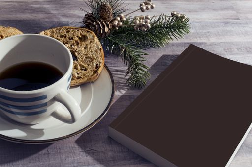 A morning coffee mug for breakfast, a gray notebook and Christmas tree branches on wooden table