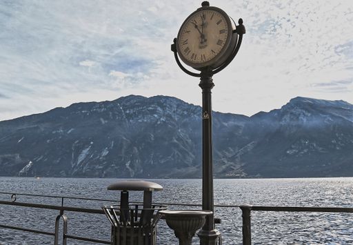 A street clock on a column in the background of the lake andmountains.