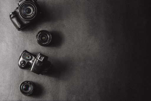 A top view of professional cameras with different lenses isolated on black background with copy space