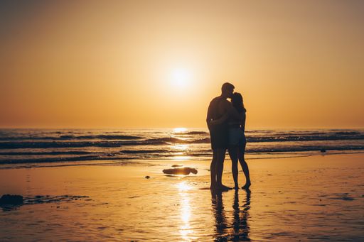 A beautiful sunset view of the beach in Spain and a loving couple.