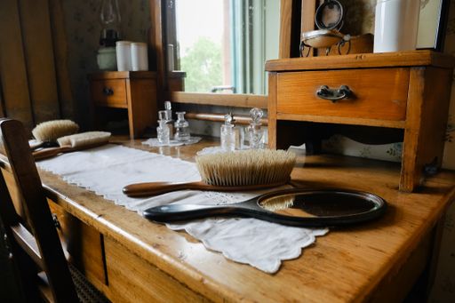 A closeup shot of a Mirror and brushes on a table with a doily, interior design.
