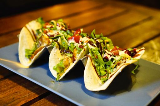 A closeup shot of tacos on a tray on the table under the lights - perfect for food concepts