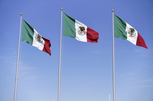 A low angle shot of three Mexican Flags on poles under the sunlight at daytime