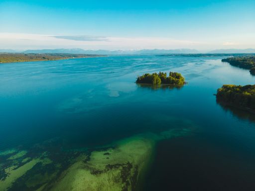 Aerial view of the Rose Island in Lake Starnberg. Deep blue water with beautiful view of a small harbour with sailing boats and the Alps background