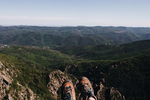 A high angle shot of a person's feet hanging from the edge overlooking the beautiful valleys