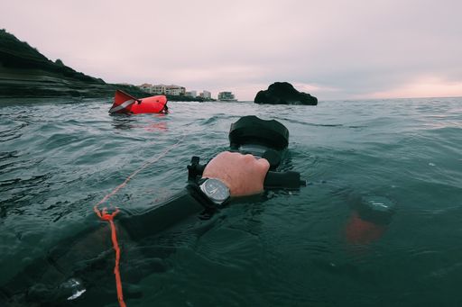 A high angle shot of a person holding a waterproof camera near the surface of the water