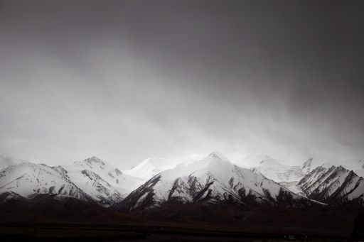 A dramatic black-and-white shot of the snowy Kunlun Mountain in Qinghai, China