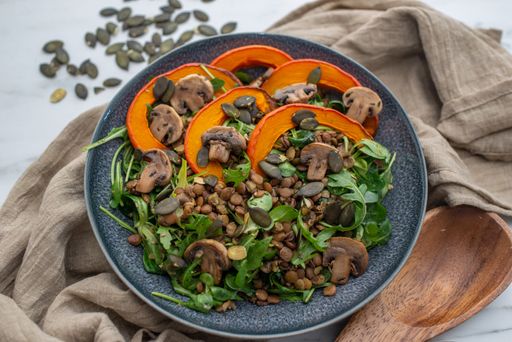 A top view of a lentil salad with greens served on a blue plate