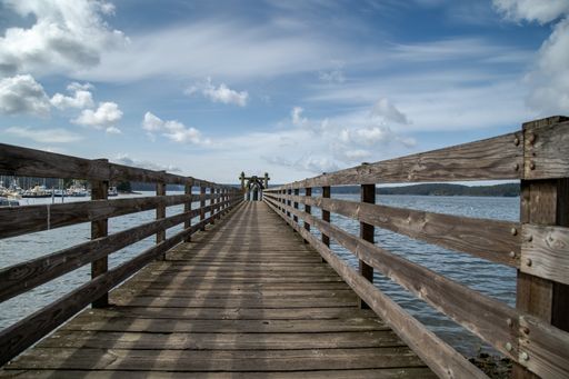 A beautiful view of the long wooden bridge leading over the sea on a cloudy day