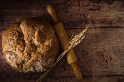 A top view of homemade bread with rolling pin on a wooden surface