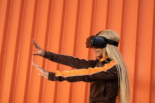 A Pretty African American woman using virtual reality glasses on an orange background