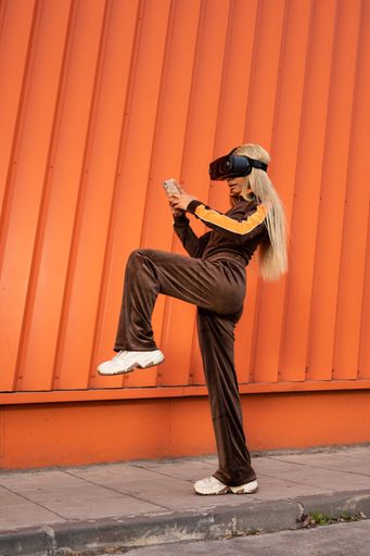 A Pretty African American woman using virtual reality glasses on an orange background