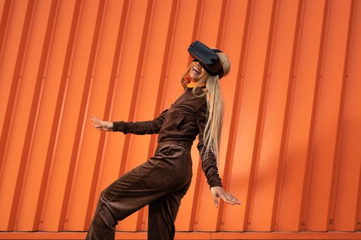 A Pretty African American woman using virtual reality glasses on an orange background