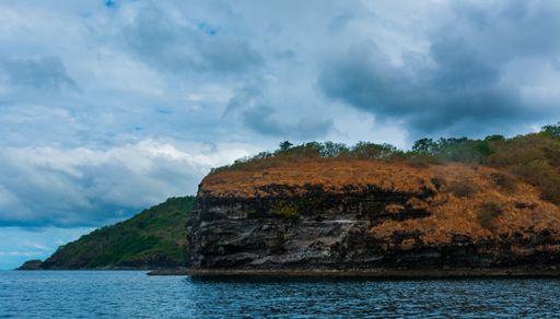 The rock Island over scenic blue seawater against a cloudy sky