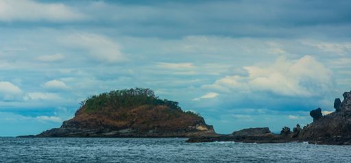 The rock Island over scenic blue seawater against a cloudy sky