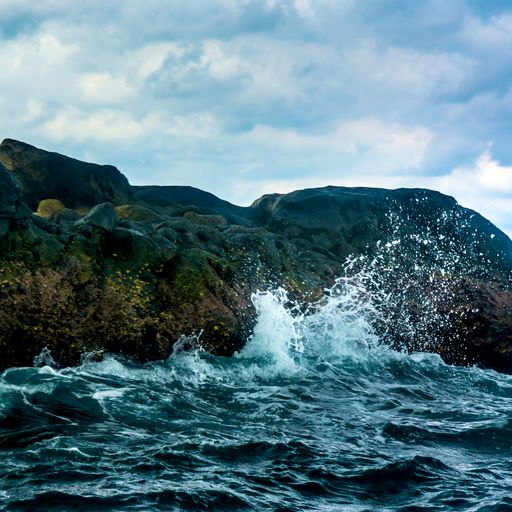 The rock Island over scenic blue seawater against a cloudy sky