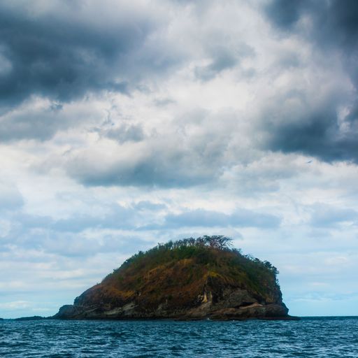 The rock Island over scenic blue seawater against a cloudy sky