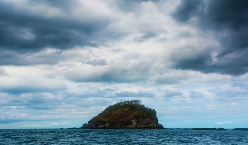 The rock Island over scenic blue seawater against a cloudy sky