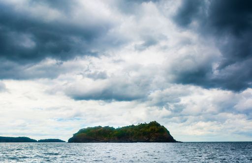 The rock Island over scenic blue seawater against a cloudy sky