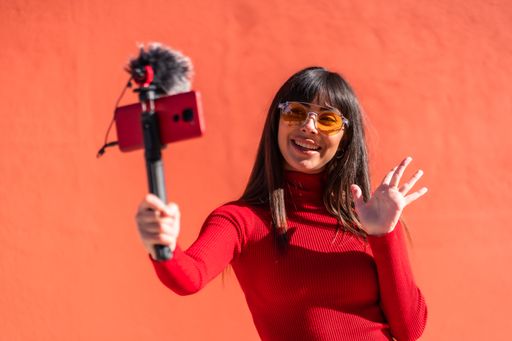 A closeup of a brunette girl recording a vlog in a red dress