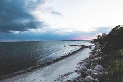 A high angle shot of the rocky beach by the ocean under beautiful colorful sky