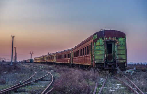 The old rusty train on the rails during sunset