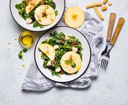 A top view of two servings of salad with spinach, apple, and other healthy ingredients